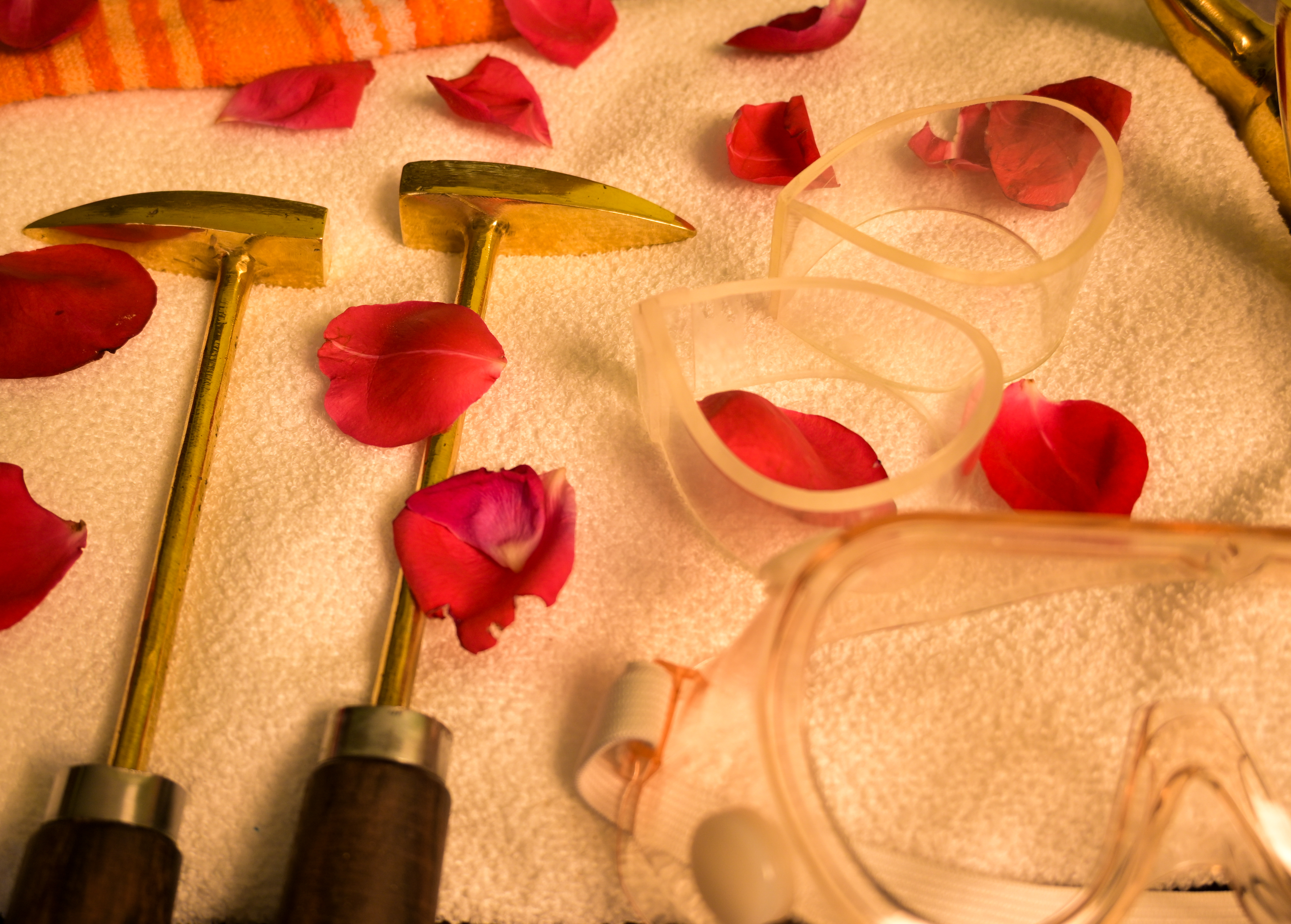 Ayurveda tools, goggles, and rose petals arranged for a therapy.